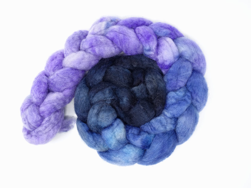 A gradient dyed braid of fibre that transitions from french navy to blue to lilac.