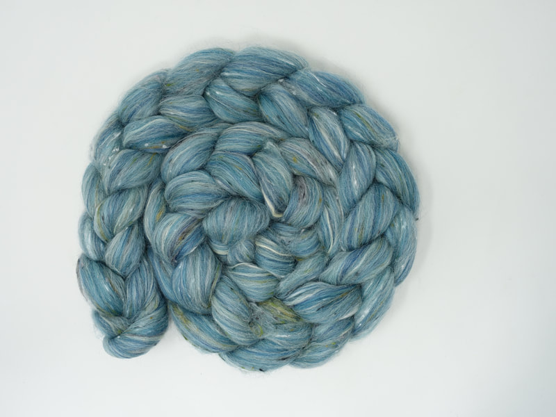 A braid of turquoise fibre with white streaks and olive green tweed nepps. 