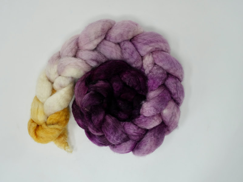 A braid of fibre that transitions from aubergine getting gradually paler to white, with a splash of ochre yellow.