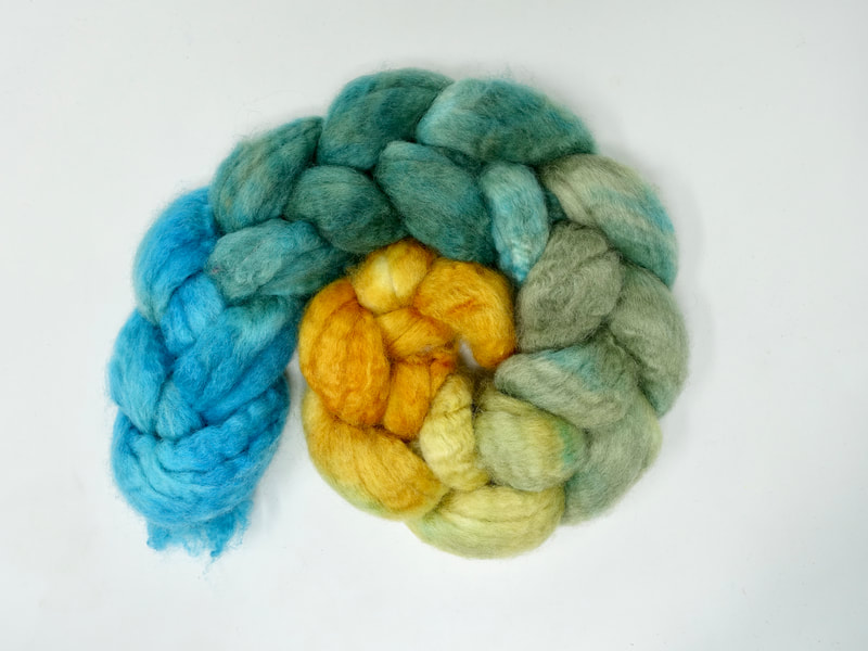 A braid of fibre that transitions from ochre yellow, to teal to turquoise