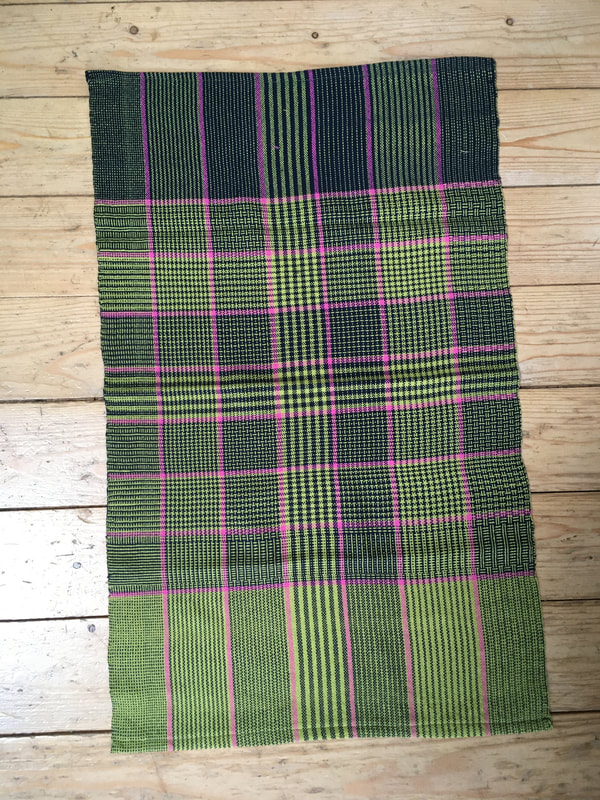 A tea towel with green, lime and pink stripes. One end is woven with green weft, the other with navy,  with the central section using the same complex pattern of the warp as in the weft.