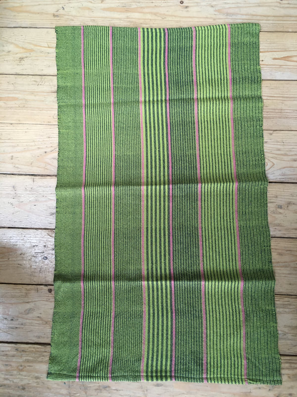A tea towel with green, lime and pink stripes. The weft uses lime green