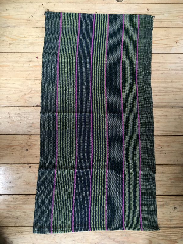 A tea towel with green, lime and pink stripes. The weft uses a dark navy