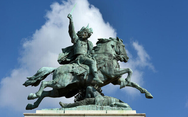 Statue of a man on a horse; the horse is trampling a Roman soldier